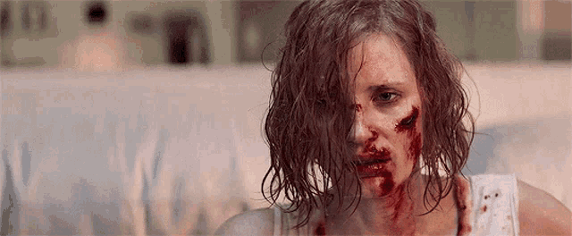 a woman with blood on her face is sitting on a couch and looking at the camera .