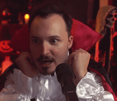 a man in a vampire costume with a red cape around his neck