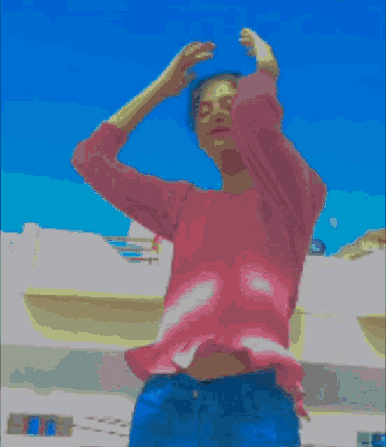 a girl in a pink shirt and blue jeans is standing in front of a building