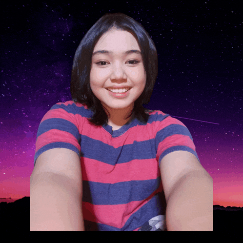 a woman in a pink and blue striped shirt smiles