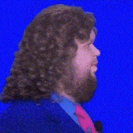 a man with curly hair and a beard is wearing a blue suit and pink tie