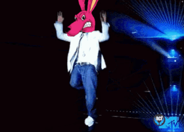 a man in a pink bunny mask is dancing on a stage