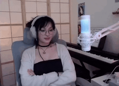 a woman wearing headphones and a choker is sitting in front of a piano .