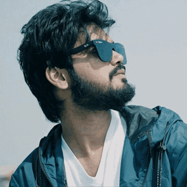 a man with a beard wearing sunglasses and a blue jacket