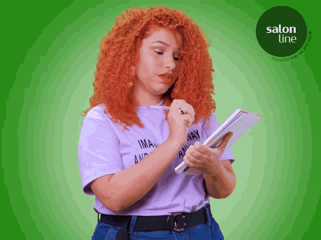 a woman with red hair is writing in a notebook with a salon line logo in the corner