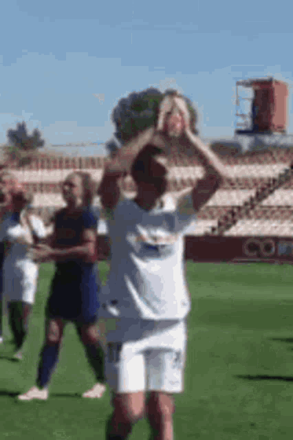 a soccer player is standing on a field holding a trophy in his hands .