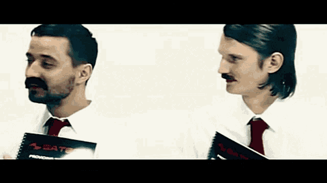 two men wearing white shirts and red ties are holding a book that says " sate "