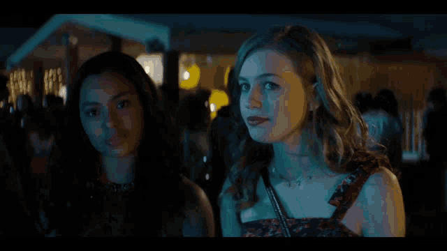 two women are standing next to each other in a crowded area