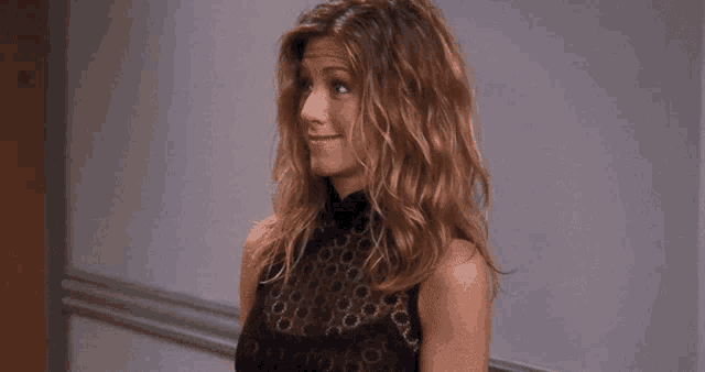 a woman with curly hair is wearing a black dress and smiling .