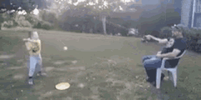 a man is sitting in a chair while a boy throws a frisbee .