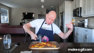 a man wearing an apron that says quiksilver cuts a pizza