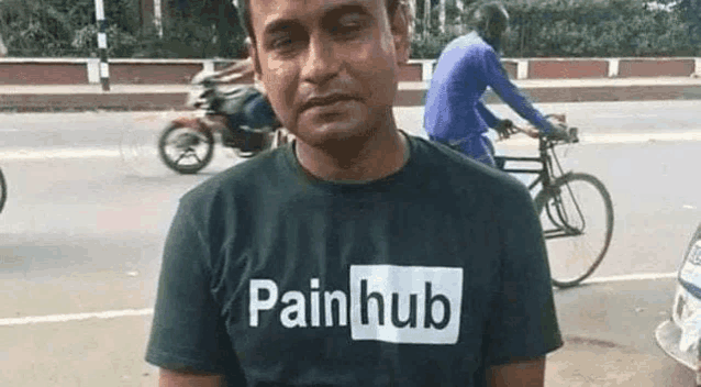 a man wearing a t-shirt that says `` pain hub '' is standing on the side of the road .