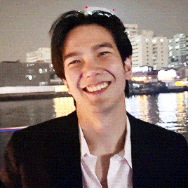 a man in a suit and tie is smiling in front of a river
