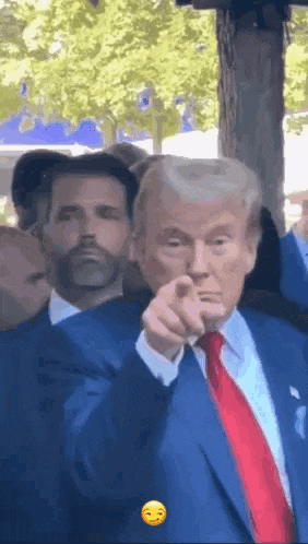 a man in a blue suit and red tie is pointing at something