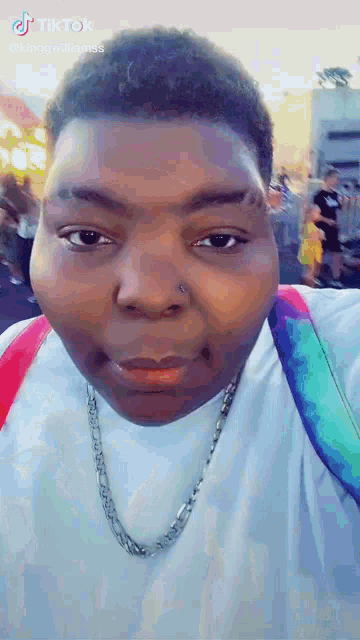 a close up of a person 's face with a chain around their neck and a backpack .