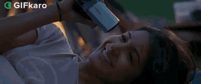 a woman is laying in bed with her head on a pillow in front of a fire .