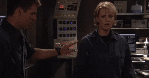 a man and a woman are shaking hands in front of a control panel that shows the time as 2:27