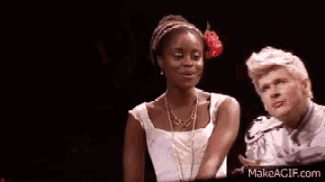 a man and a woman are standing next to each other on a stage and the woman has a flower in her hair .