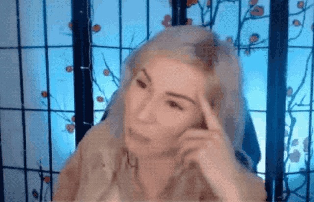 a woman with blonde hair is sitting in front of a screen with flowers on it