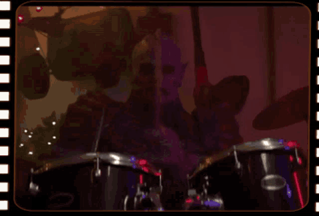 a blurred image of a man playing drums in a dark room