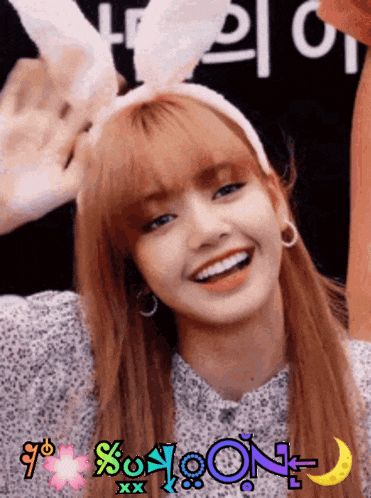 a woman wearing bunny ears and hoop earrings smiles in front of a sign that says % oon