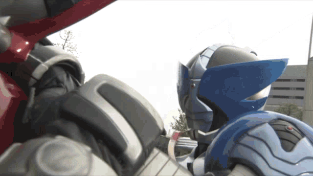 two robots are standing next to each other and one has a blue wing on it