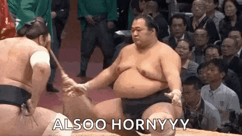 two sumo wrestlers are wrestling in front of a crowd and one of them is holding a stick in his hand .