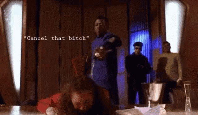 a man in a blue shirt says " cancel that bitch " in front of a group of people