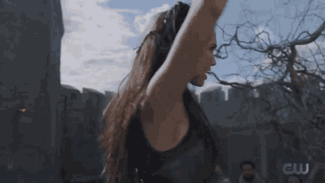 a woman with long hair is standing in front of a castle with her arms outstretched .