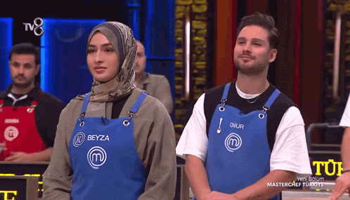 a man and a woman wearing blue aprons that say beyza on them