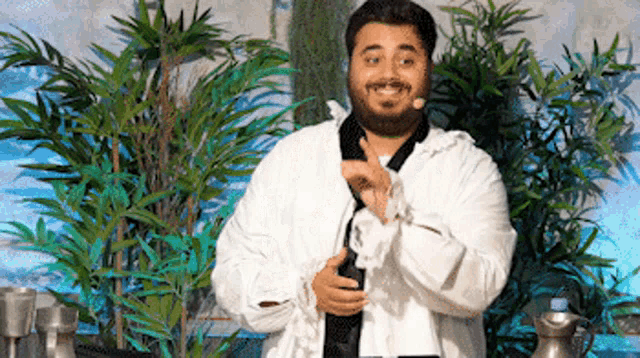 a man with a beard is wearing a white robe and holding a bottle .