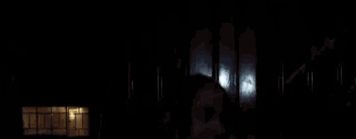 a young girl is standing in front of a black door at night .