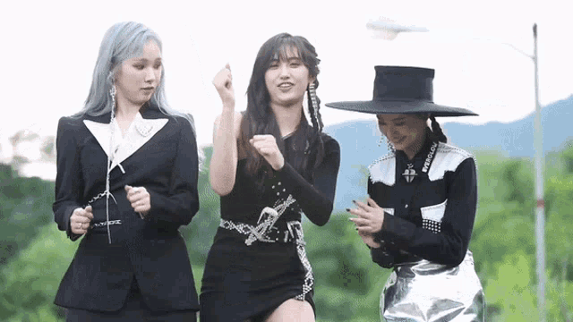 three women are standing next to each other and one is wearing a black hat