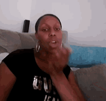 a woman sitting on a couch wearing a black shirt that says ' u ' on it
