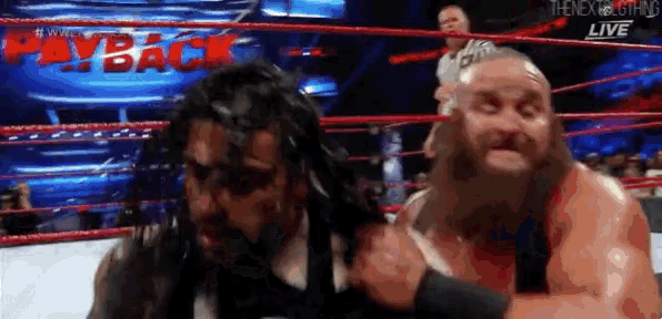 two men are wrestling in a wrestling ring and one of them has a beard .