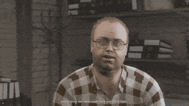 a man in a plaid shirt and glasses says " think back to "