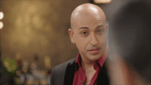 a bald man with a red shirt and a black jacket