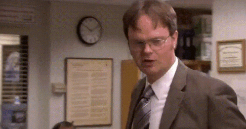 a man in a suit and tie is standing in front of a wall clock .