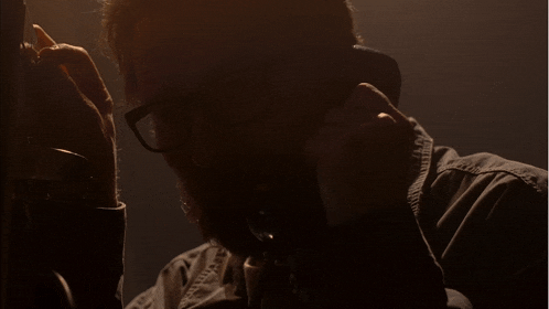 a man with glasses is talking on a phone and the words please are visible in yellow