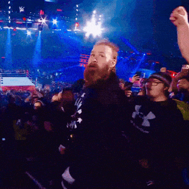 a man in a black under armour shirt stands in a crowd