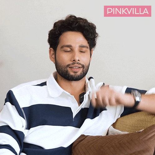 a man wearing a striped shirt is sitting on a couch with his eyes closed and a pink villa logo behind him