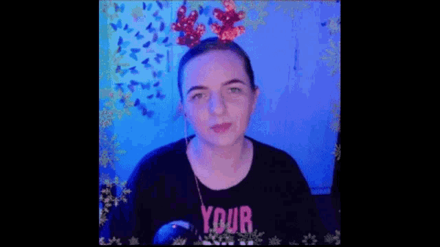 a woman wearing a christmas reindeer headband and a black t-shirt with the word your on it .