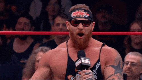 a man in a wrestling ring with a microphone that says ' roh ' on it