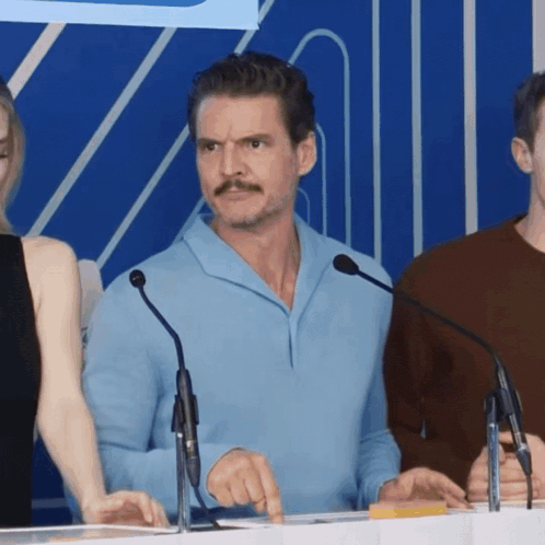 a man with a mustache stands in front of a microphone