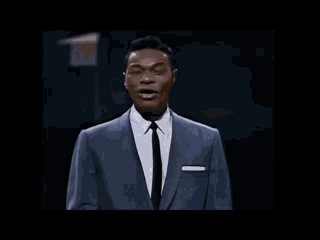 a man in a suit and tie is standing in front of a black background