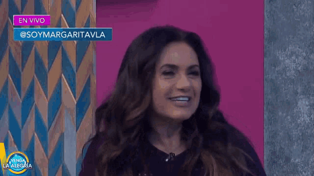 a woman is smiling in front of a sign that says en vivo on it