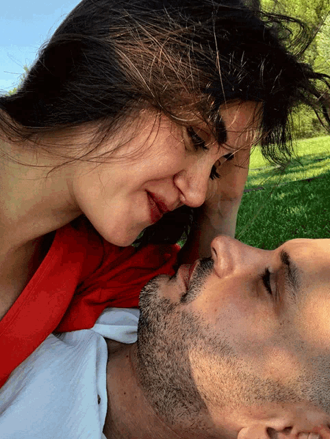 a woman kissing a man 's forehead in a park