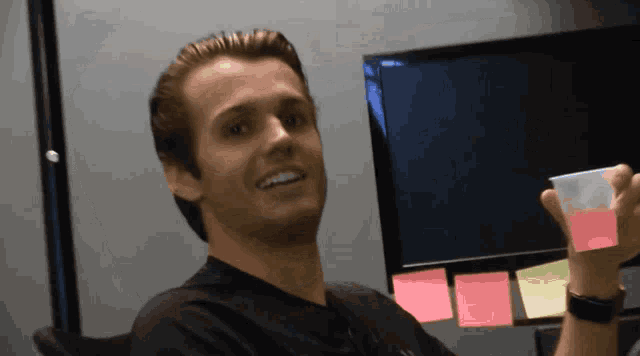 a man in a black shirt is smiling while holding a plastic cup