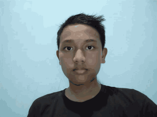 a young man in a black shirt looks at the camera with a blue background