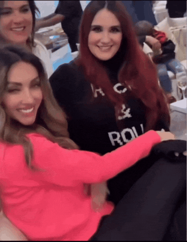 a woman wearing a sweater that says ' dolce & gabbana ' on it is hugging another woman